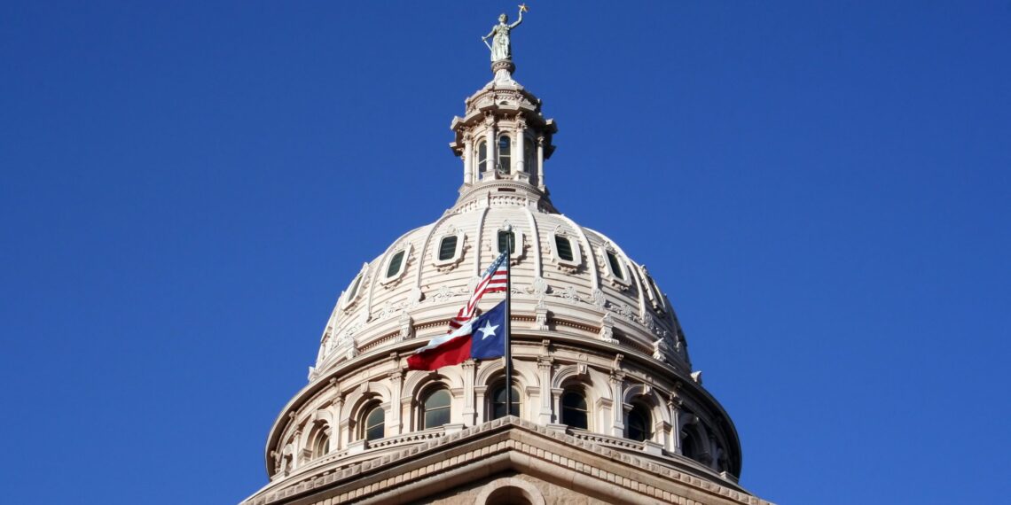 Texas and U.S. flags flying at the Texas State Capitol building