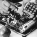 Man's hands placing a wiretap inside an old fashioned telephone