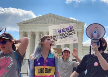 protesters shouting and holding signs in front of supreme court