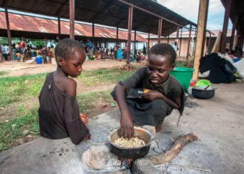 Two children cook maize at a camp for displaced people in Malawi.