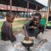 Two children cook maize at a camp for displaced people in Malawi.