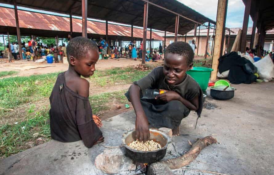 Two children cook maize at a camp for displaced people in Malawi.