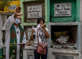 Catholic priest Flaviano Villanueva blesses the tomb of Lome Codilla, a victim of an alleged extrajudicial killing five years ago, before his remains are exhumed.