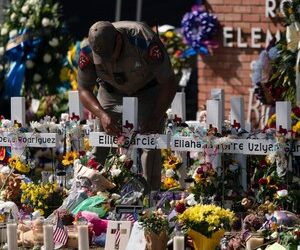 A state trooper places a tiara on a cross honoring Ellie Garcia, one of the victims killed in this week's elementary school shooting in Uvalde, Texas Saturday, May 28, 2022.