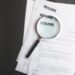Top view of stack of resume files,magnifier on black surface.Concept of reviewing resume applictaions,searching for new employees