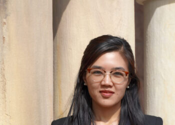 Rosalinn Zahau standing in front of pillars and wearing a black top and black blazer.