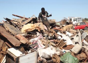 Colin Mapuranga sits on a pile of metal in a scrap yard near Hopley, a settlement outside Harare.