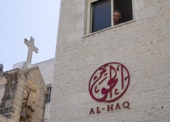 A man looks out of the window of the office of Al-Haq after it was raided in the West Bank city of Ramallah