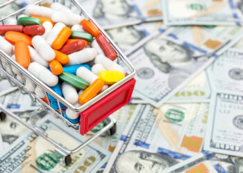 Full shopping cart with pills on background of dollar bills. Close up. Space for text.