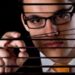 Young man looking through a window blind Spying
