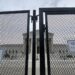 close up photo of chain-link security fence with front of supreme court building visible in background through the fence