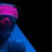 Blue female cyber with neon pink META VERSE LOADING text goggles on geometric dark background
