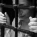 Young woman behind prison bars