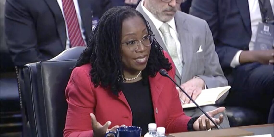 ketanji brown jackson sitting behind microphone with palms turned upward