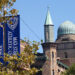 view of domed building with vertical banners and tree branches in foreground