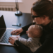 Working mother at a laptop with a baby