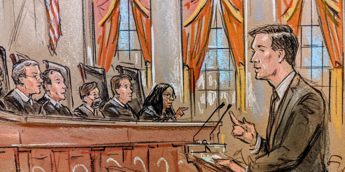 profile view of man at the podium arguing before five justices