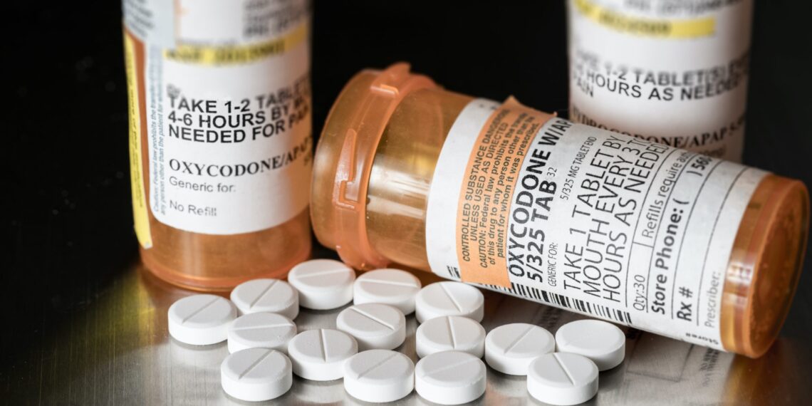 pill bottles bearing an oxycodone label, with pills lying on table