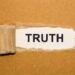 The text Truth appearing behind torn brown paper