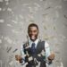 happy man pumping fists celebrates success under money rain