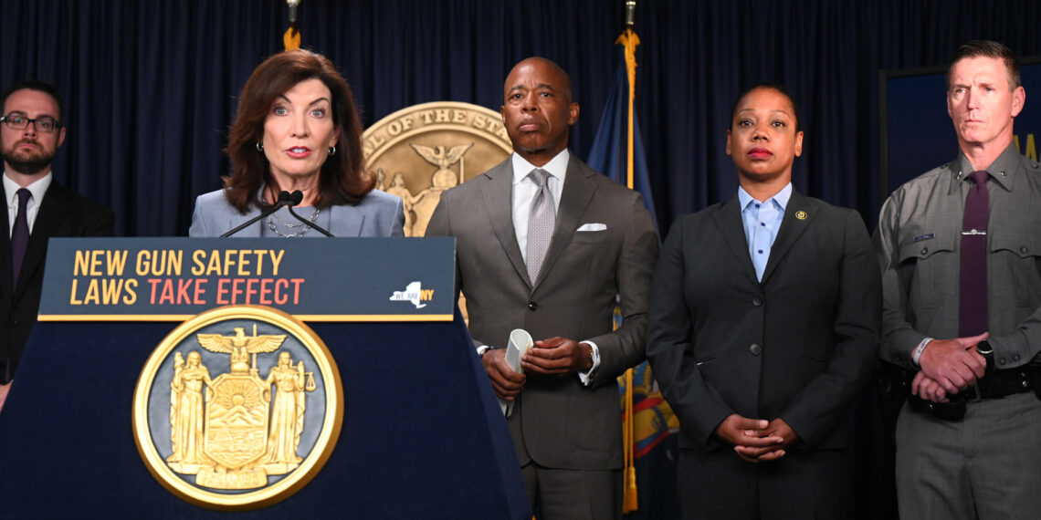 Woman speaking at podium with four people standing behind her.