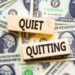 Quiet quitting symbol. Concept words Quiet quitting on wooden blocks. Beautiful background from dollar bills. Business and quiet quitting concept. Copy space.
