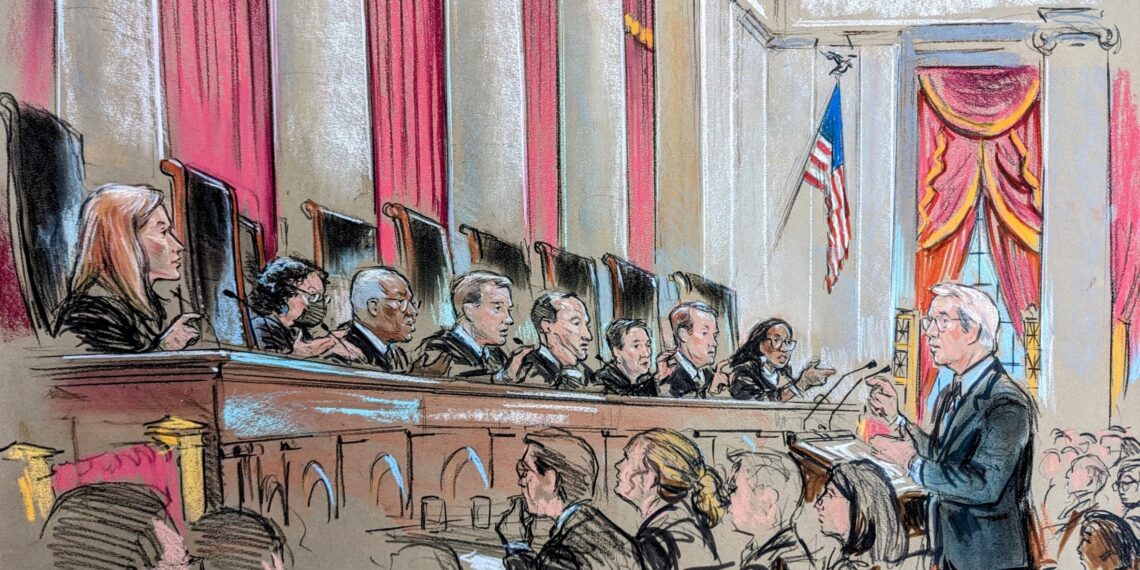 A man speaks at a lecture before nine justices on the bench who all seem to be asking him a question.