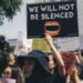 Picture of a poster at a protest stating "we will not be silenced"
