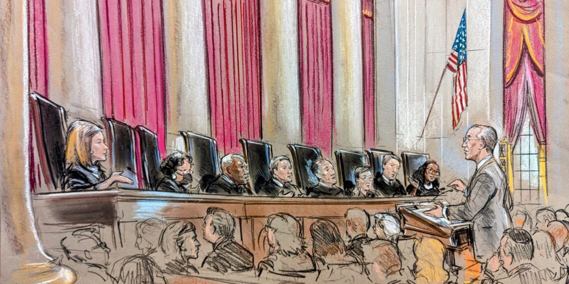 Eight justices on the bench speaking to and watching a man at the podium in a crowd of people.