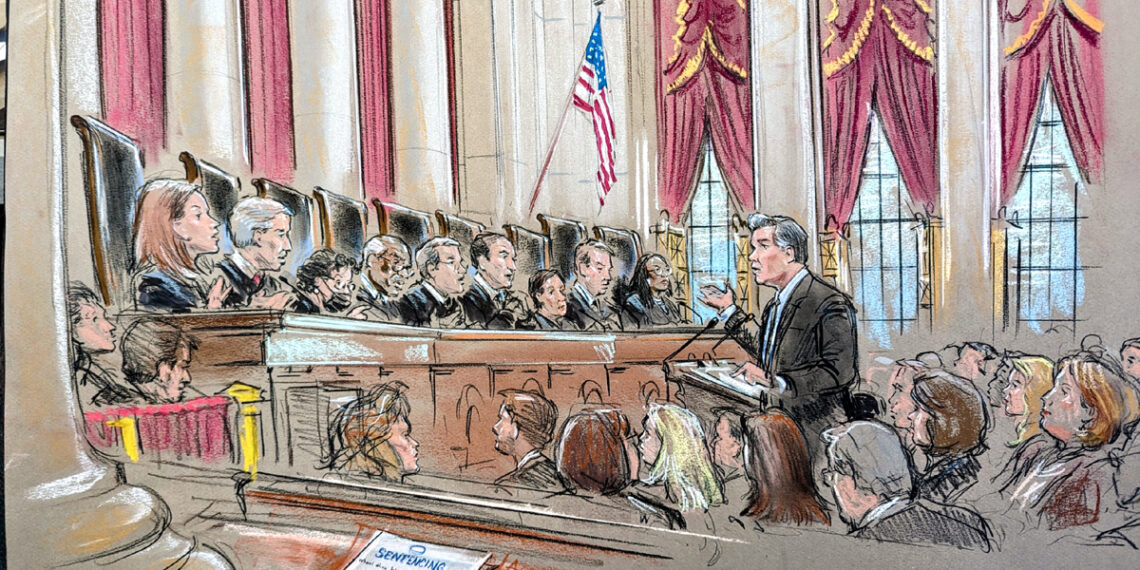 A wide shot of the court room. A man speaks from the lectern surrounded by a crowd as the justices speak from the bench.