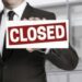 Businessman holding closed sign to viewer
