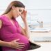 Pregnant woman at work with laptop looking stressed