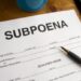 Subpoena form with a pen on a wooden desk