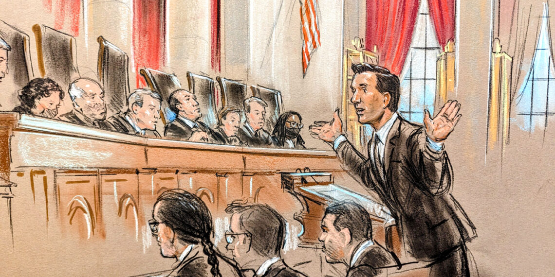 Man speaking with hands raised in front of nine justices on the bench