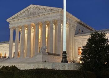 front of supreme court building illuminated against a dark sky