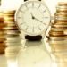 A timepiece and stacks of coins