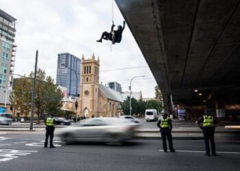 A woman abseils over a bridge in Adelaide during an Extinction Rebellion protest on 18 May.