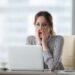 email fail palm Shocked young woman looking at laptop screen.