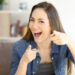 Excited woman pointing at camera at home