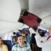Flight attendant putting luggage in overhead bin in airplane
