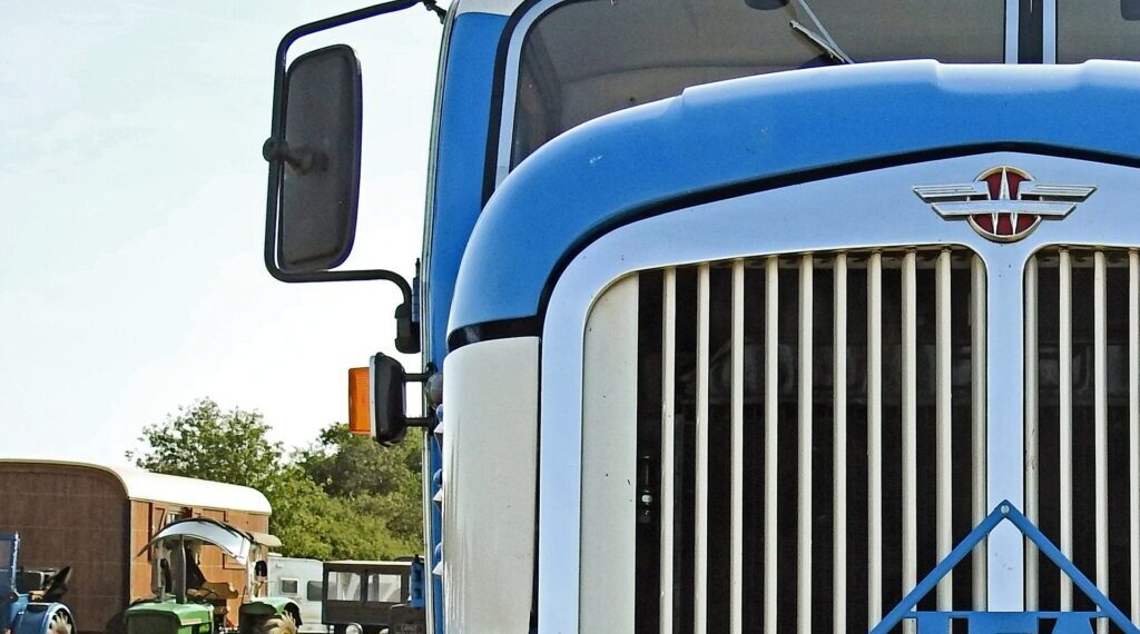 A blue big rig truck from the grill up focused on the large side mirror