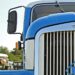 A blue big rig truck from the grill up focused on the large side mirror