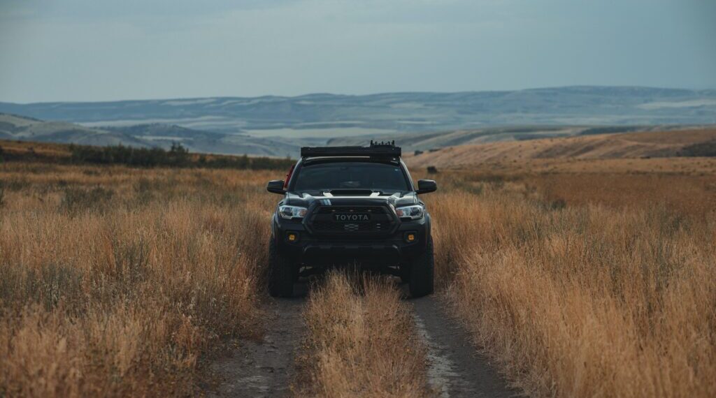 A car in the middle of a field in the dusk with its lights off