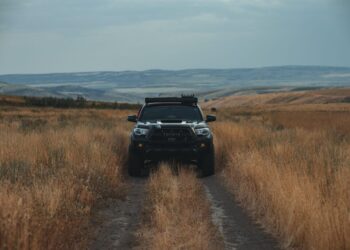 A car in the middle of a field in the dusk with its lights off