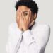 Afraid african woman hiding face with hands peeping through fingers