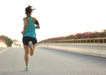 young woman runner running on city bridge road