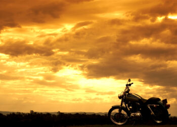 Motorcycle in the right bottom corner of a gorgeous orange sunset with clouds.