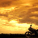 Motorcycle in the right bottom corner of a gorgeous orange sunset with clouds.
