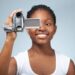 Teenage girl (15-17) using video camera, smiling, close-up