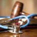 Judge’s gavel and stethoscope on court room table.